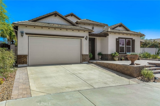 single story home with stucco siding, driveway, stone siding, a garage, and a tiled roof