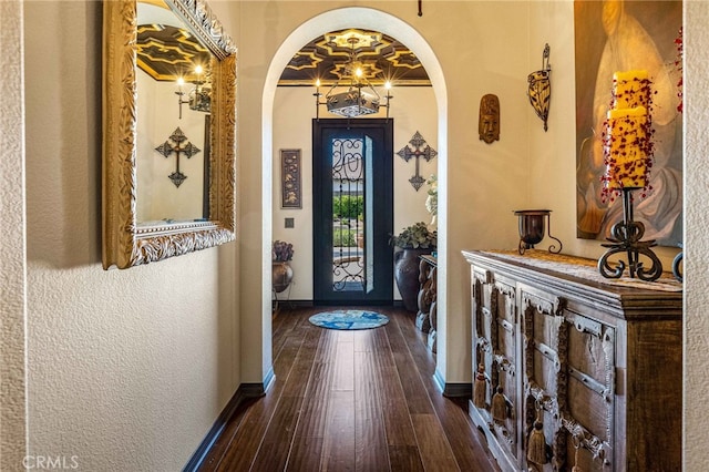 foyer with baseboards, arched walkways, and dark wood-style floors