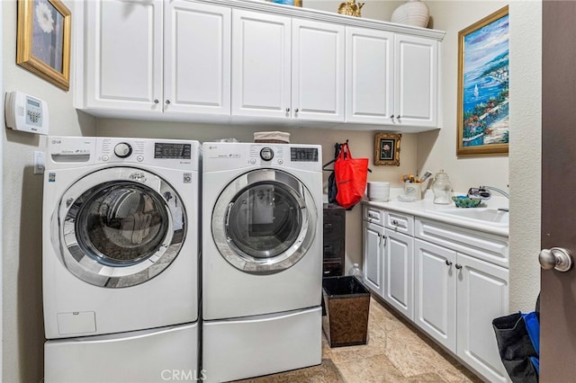 washroom featuring cabinet space, washer and dryer, stone finish flooring, and a sink