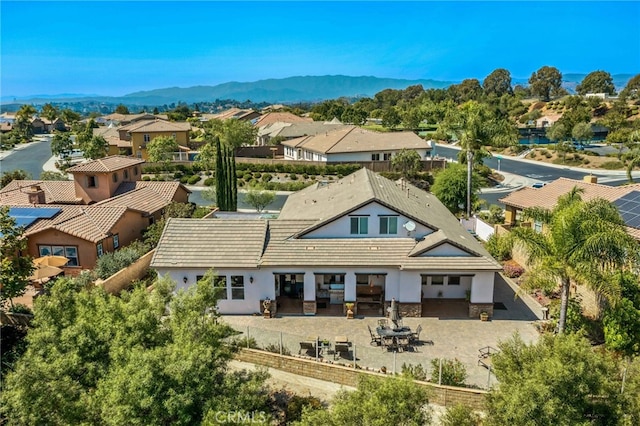 rear view of property featuring a mountain view, a patio area, a residential view, and stucco siding