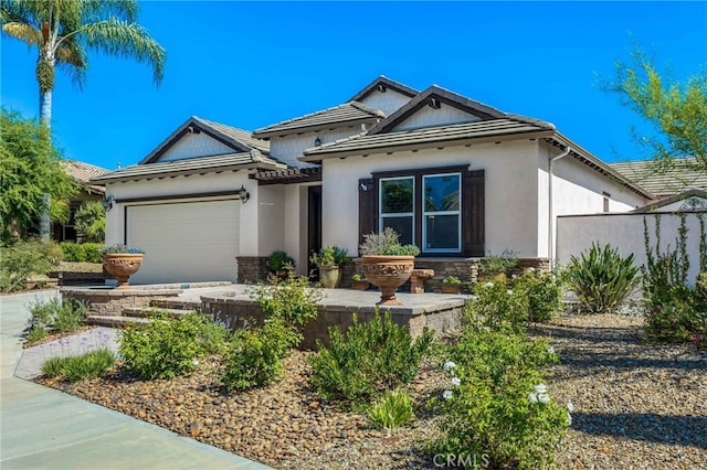 view of front of home featuring a tiled roof, a garage, and stucco siding