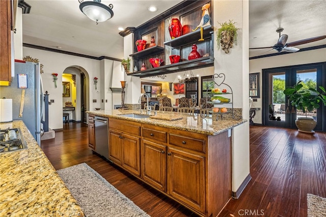 kitchen featuring a ceiling fan, a sink, dark wood-style floors, stainless steel appliances, and arched walkways