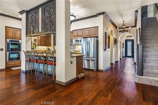 kitchen with dark hardwood / wood-style floors, light stone countertops, stainless steel appliances, and ornamental molding