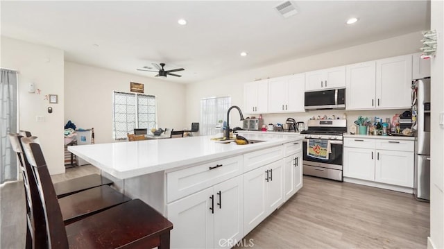 kitchen featuring sink, white cabinetry, appliances with stainless steel finishes, and a center island with sink