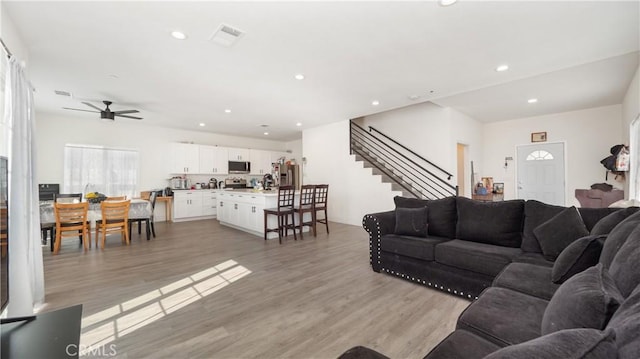 living room featuring ceiling fan and light hardwood / wood-style flooring