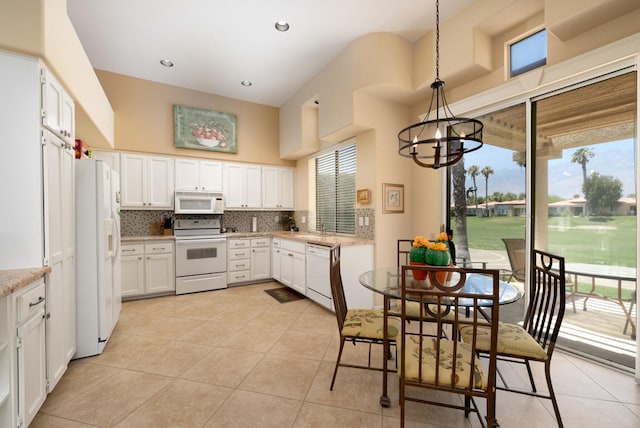 kitchen with white appliances, white cabinetry, a wealth of natural light, and decorative light fixtures