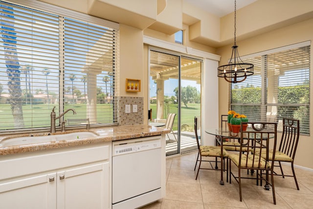 kitchen with hanging light fixtures, white cabinetry, dishwasher, light tile patterned flooring, and sink