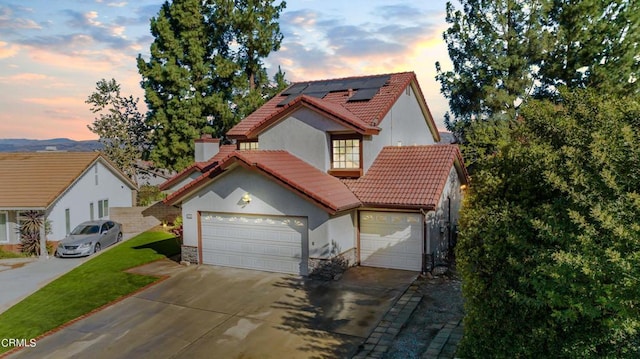 view of front of property featuring solar panels, a yard, and a garage