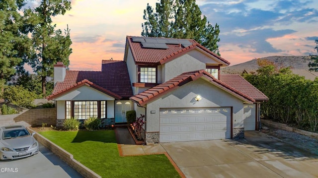 view of front of home featuring a lawn, a mountain view, a garage, and solar panels