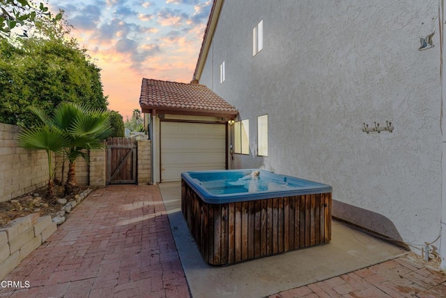 patio terrace at dusk featuring a hot tub