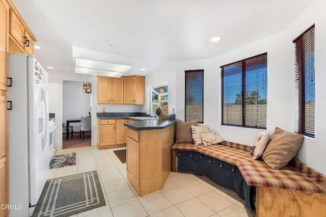 kitchen featuring light tile patterned floors, white refrigerator with ice dispenser, sink, and light brown cabinetry