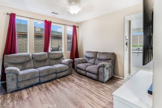 living room featuring ceiling fan, sink, and light wood-type flooring