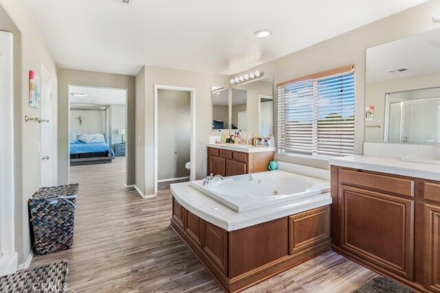 full bathroom with vanity, independent shower and bath, hardwood / wood-style flooring, and toilet