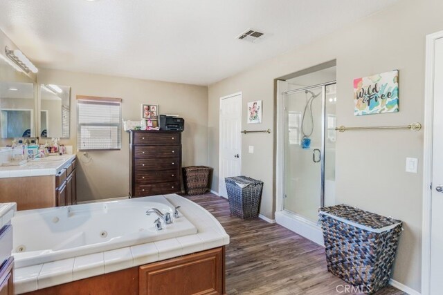 bathroom with vanity, hardwood / wood-style floors, and plus walk in shower