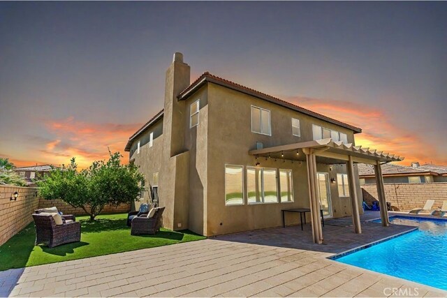 back house at dusk featuring a patio area, a fenced in pool, and a pergola