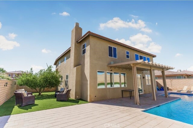 rear view of property featuring a fenced in pool and a pergola