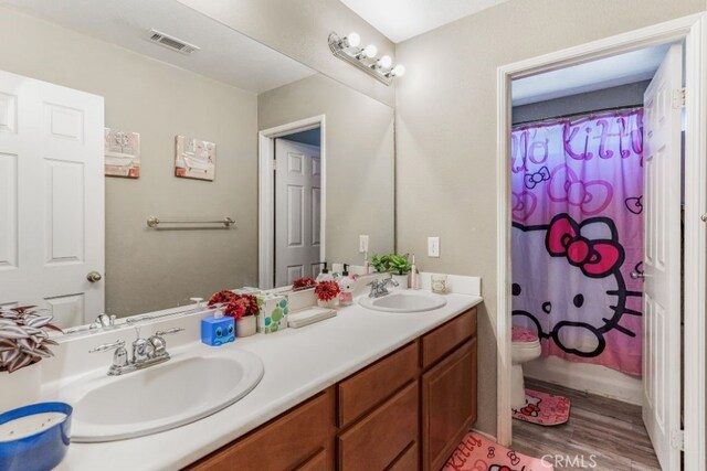 bathroom featuring toilet, curtained shower, hardwood / wood-style flooring, and vanity