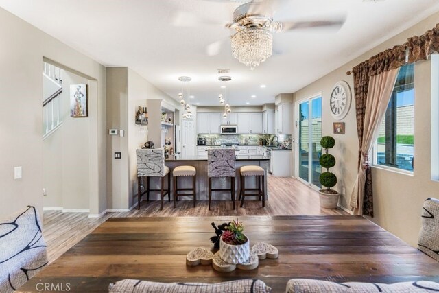 kitchen featuring kitchen peninsula, hanging light fixtures, a breakfast bar, hardwood / wood-style flooring, and sink