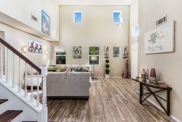 living room featuring a towering ceiling, plenty of natural light, and hardwood / wood-style floors