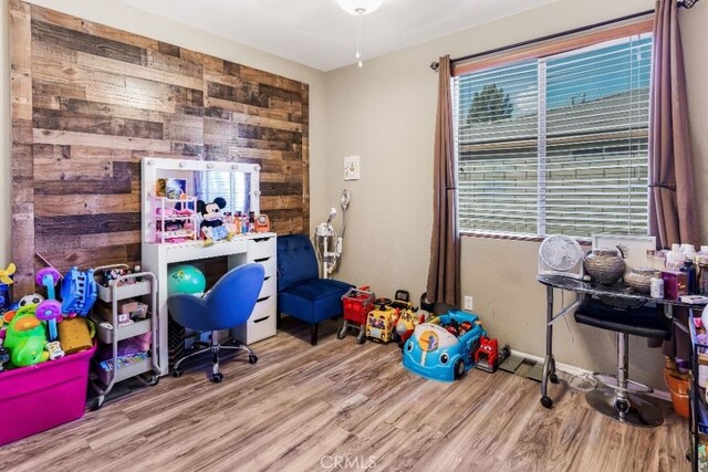 office space featuring light hardwood / wood-style floors, wood walls, and ceiling fan