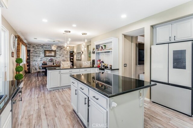 kitchen with kitchen peninsula, white cabinetry, light hardwood / wood-style floors, pendant lighting, and white fridge