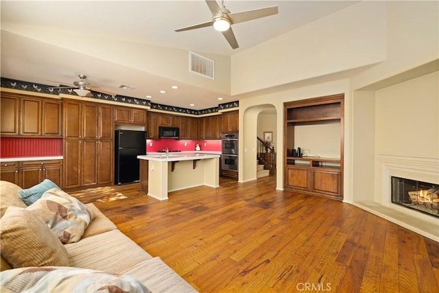 unfurnished living room with ceiling fan, sink, dark wood-type flooring, and a high ceiling