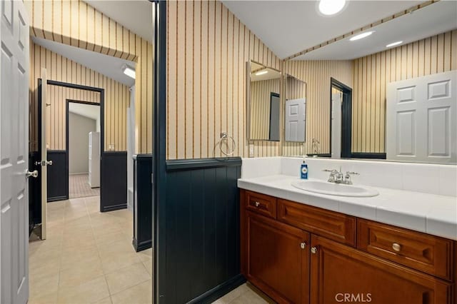 bathroom with tile patterned flooring, vanity, and lofted ceiling