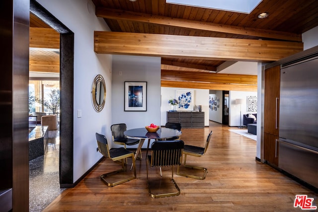 dining space featuring a skylight, wooden ceiling, light hardwood / wood-style floors, and beamed ceiling