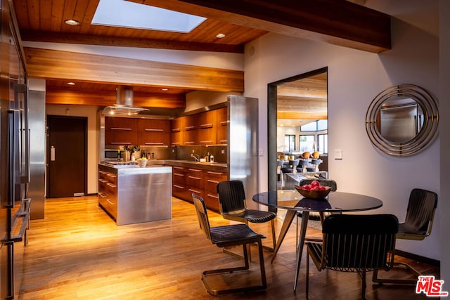 kitchen with a kitchen island, appliances with stainless steel finishes, vaulted ceiling with skylight, light hardwood / wood-style floors, and wooden ceiling