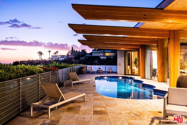 pool at dusk featuring a patio area