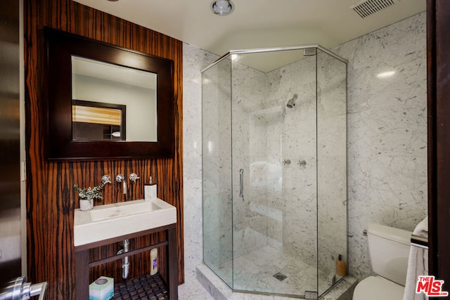 bathroom featuring vanity, a shower with door, and toilet