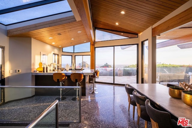 dining area featuring beamed ceiling, bar, high vaulted ceiling, and wooden ceiling