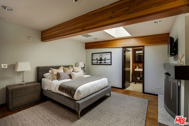 bedroom featuring a skylight, beam ceiling, and light hardwood / wood-style flooring