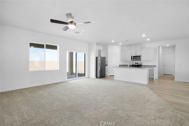 unfurnished living room with ceiling fan and light hardwood / wood-style floors