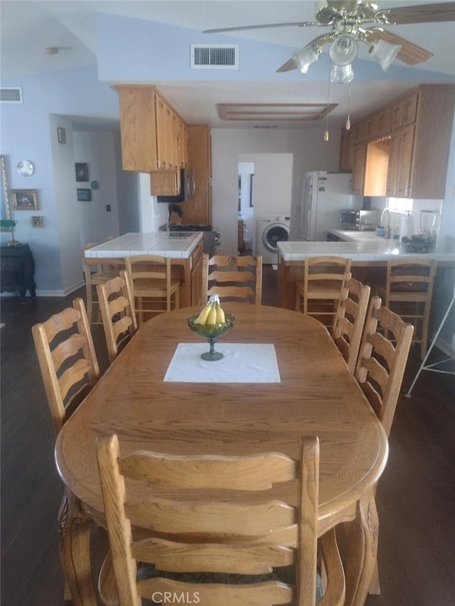 dining room with washer / dryer, ceiling fan, and dark hardwood / wood-style floors