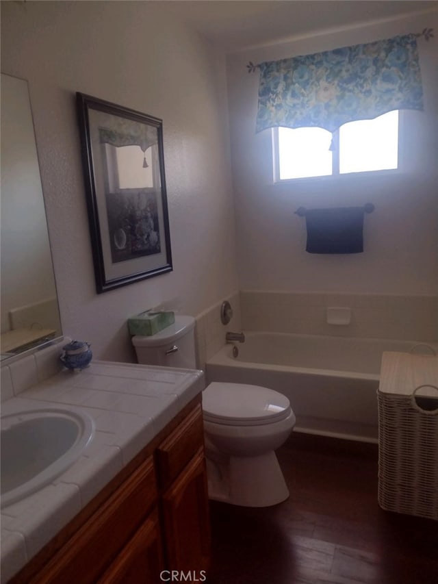 bathroom featuring a bath, toilet, wood-type flooring, and vanity