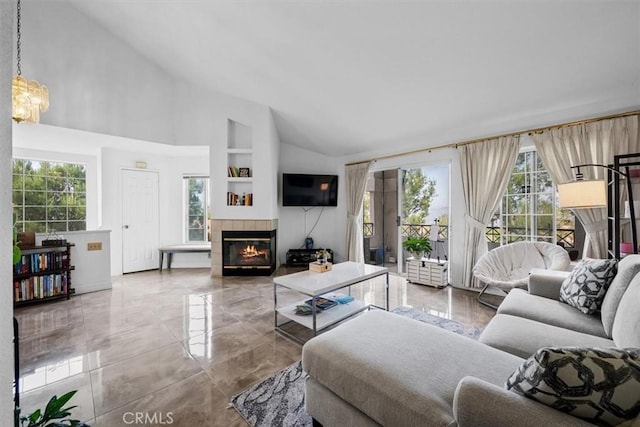 living room featuring a tile fireplace, lofted ceiling, and an inviting chandelier