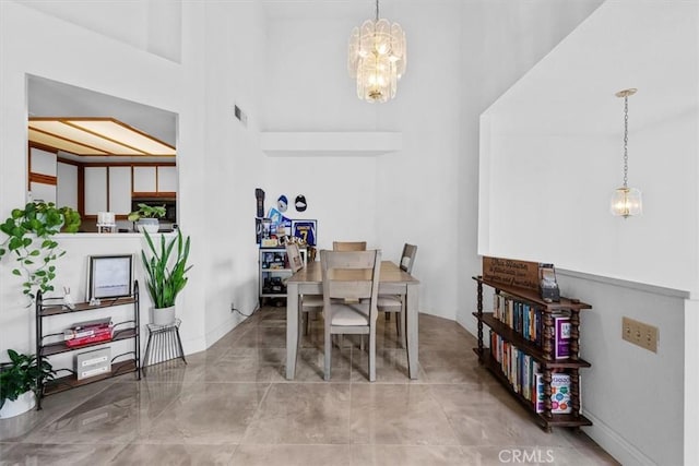 dining area featuring an inviting chandelier and a towering ceiling