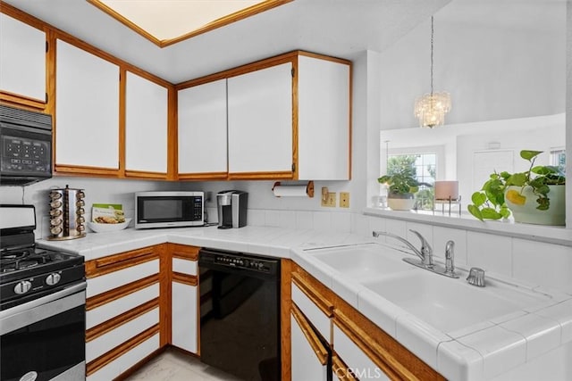 kitchen with white cabinets, black appliances, decorative light fixtures, sink, and a chandelier