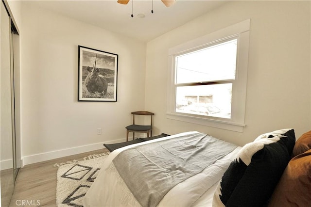 bedroom with ceiling fan, a closet, baseboards, and wood finished floors