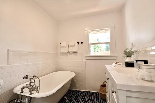 full bathroom featuring a freestanding tub, tile walls, and vanity