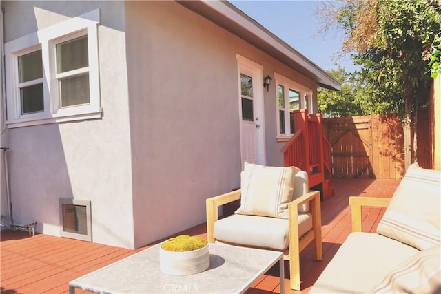 exterior space featuring a wooden deck, fence, and stucco siding