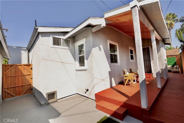 back of property featuring fence, visible vents, and stucco siding