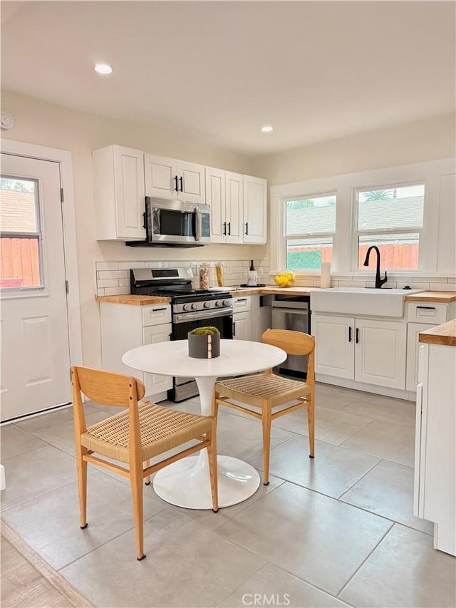 kitchen featuring recessed lighting, a sink, light countertops, white cabinets, and appliances with stainless steel finishes