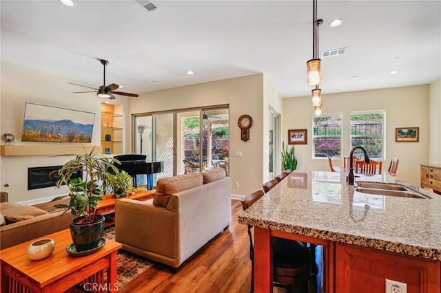 living room featuring ceiling fan, sink, hardwood / wood-style floors, and built in features