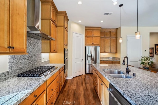 kitchen featuring wall chimney range hood, pendant lighting, sink, dark wood-type flooring, and stainless steel appliances