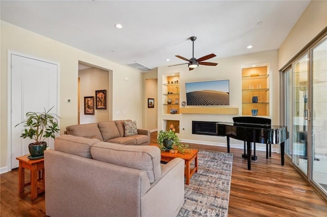 living room with ceiling fan, built in features, and dark hardwood / wood-style flooring