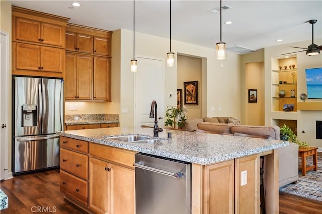 kitchen featuring an island with sink, appliances with stainless steel finishes, decorative light fixtures, built in features, and sink