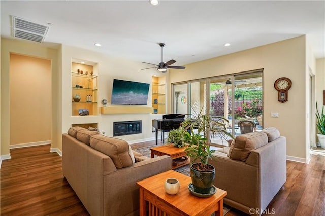 living room with ceiling fan, dark hardwood / wood-style flooring, and built in shelves