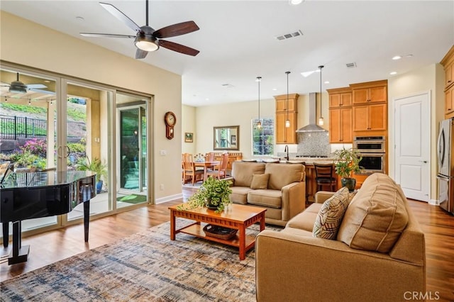 living room featuring ceiling fan and light hardwood / wood-style floors